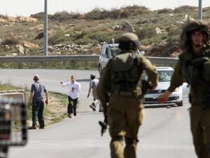 Israeli soldiers are seen close to settlers who are attacking a photographer's car, near illegal settlement of Beit El. (AFP/File)