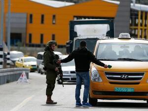 An Israeli soldier checks the documents of a Palestinian passenger of a taxi. (AFP/File)