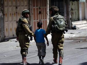 Israeli soldiers arrest a young Palestinian boy following clashes in the center of the West Bank town of Hebron, on June 20, 2014. (AFP/File)