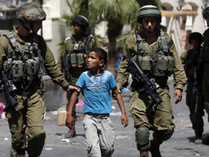 Israeli forces detain a Palestinian boy following clashes in the centre of the West Bank city of Hebron, on June 20, 2014. (AFP/File)