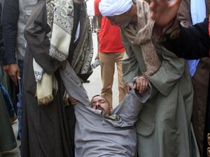 A relative of a supporter of Egyptian ousted Islamist president Mohamed Morsi is supported as he faints outside the courthouse on March 24, 2014 in the central Egyptian city of Minya, after the court ordered the execution of 529 Morsi supporters after only two hearings. (AFP/File)