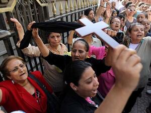 An Egyptian Coptic Christian raises a cross while others shout slogans in a demonstration last year. (AFP/File)