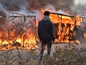 A refugee looks at shacks burning during the dismantling of the "Jungle" migrant camp in Calais, on February 29, 2016. (AFP/Philippe Huguen) 