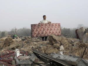 A Palestinian man carries a mattress at the rubble of a destroyed building following a military attack on his home. (AFP/File)