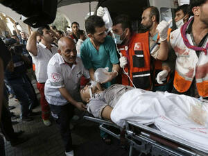 Palestinian paramedics carry a man wounded in a strike at a marketplace in the Shejaiya neighborhood. (AFP/File)