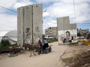 A Palestinian rides a cart past a mural on March 30, 2016, in Khan Yunis, in the southern Gaza Strip. (AFP/Said Khatib)
