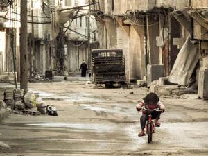 A Syrian girl rides her bicycle in an almost deserted street in the Teshrin neighborhood of the Qabun area in Damascus on 3 January 2013. (AFP/Omar Al-Khani)