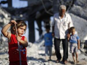 A Palestinian girl plays in the rubble of buildings destroyed during the 50-day 2014 Israeli war in Gaza City, July 21, 2015. (AFP/File)