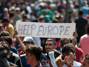 Man holds a placard reading "Help Europe" as Syrian and Afghan refugees attend a protest to demand to travel to Germany on September 2, 2015 in Budapest. (AFP/File) 