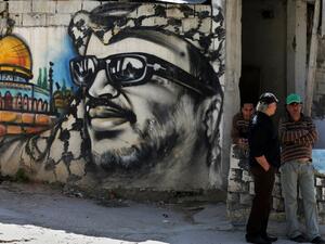 Palestinian refugees stand next to graffiti bearing a portrait of late Palestinian President Yasser Arafat at the Ain Al-Helweh refugee camp. (AFP/File)