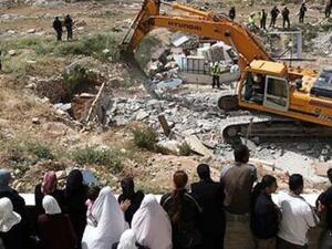 Palestinians watch an Israeli excavator destroying a Palestinian house in a village in the West Bank. (AFP/File)