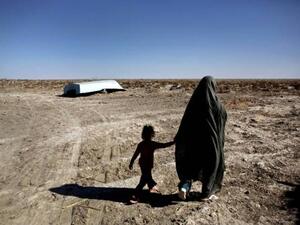 An Iranian woman and her daughter walk past an abandoned boat in the village of Sikh Sar. (AFP/File)