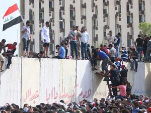 Iraqi protesters climb over a concrete wall surrounding the parliament after breaking into Baghdad. (AFP/File)