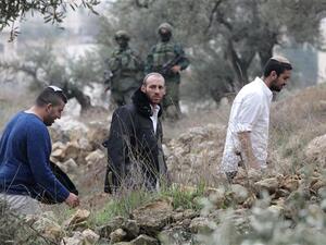 Israeli settlers walk past Israeli soldiers, who are searching Palestinian homes in the occupied southern West Bank. (AFP/File)