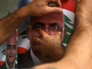 A Lebanese man puts up a poster of a candidate for the upcoming elections. (AFP/File)