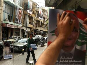A Lebanese man puts up a poster of a candidate in the Beirut municipal elections. (AFP/File)
