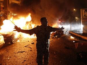 A security officer tries to keep people back as fire takes over cars at the site of a car bomb attack in Beirut. (AFP/File)