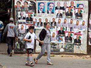 People walk past posters of Lebanese candidates running in the country's municipal election. (AFP/File)