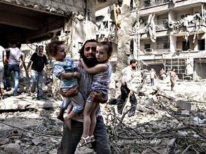 A Syrian man carries two girls as he walks across the rubble following a bombing in Aleppo. (AFP/Karam al-Masri)