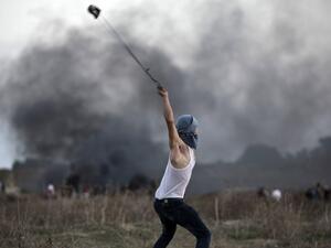 A Palestinian protester uses a slingshot to throw stones towards Israeli soldiers during clashes. (AFP/File)