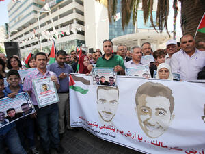Palestinians hold banners in support of borther Muhammad and Mahmoud al-Balboul, and Malik al-Qadi, in the West Bank city of Nablus, on 21 September. (AFP/File)