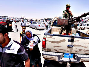 Iraqi families fleeing violence in the northern Nineveh province gather at a Kurdish checkpoint in Aski kalak, 40 km west of Erbil. (AFP/Safin Hamed)