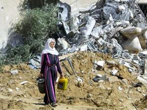 A Palestinian woman leaves what once was her home carrying a gas cooker after her house was bulldozed by the Israeli Army, a practice Human Rights Watch says could be war crime. (AFP/Said Khatib)