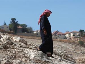 A Palestinian Bedouin walks past the Israeli settlement of Kedar in the Bedouin village of Wadi Abu Hindi, near the town of al-Azariya in the occupied West Bank, October 10, 2016. (AFP/File)