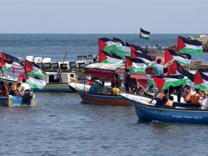 Palestinians hold their national flag as they ride boats during a rally to show support for activists aboard a flotilla of boats who are soon to set sail for Gaza in a fresh bid to break Israel's blockade, at the seaport of Gaza on June 24, 2015. (AFP/File)