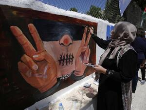 Palestinian women paint murals as they mark Palestinian Prisoner Day in the West Bank city of Ramallah on 17 April 2016. (AFP/File)