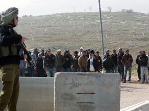 An Israeli soldier stands guard next to Palestinian workers who were transported out of the Tekoa settlement south of Jerusalem following a terror attack in the community on January 18, 2016. (AFP/Menahem Kahana)