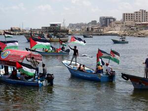 Palestinians hold their national flag as they ride boats during a rally to show support for activists aboard the flotilla. (AFP/Mahmud Hams)