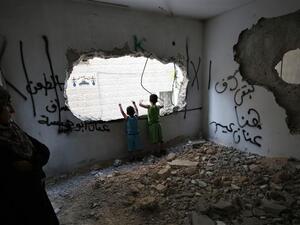 Palestinians stand at a house that was demolished by Israeli authorities in the Qalandia refugee camp. (AFP/File)
