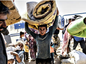 A young boy carries his bed cover. (AFP/Bulent Kilic)