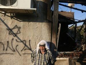 A Palestinian stands next to a graffiti reading in Hebrew "Revenge" after a house was set on fire by Jewish settlers in the West Bank village of Duma near Nablus. (AFP/Jaafar Ashtiyeh)