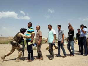 An Iraqi soldier bodychecks men in Baghdad as they arrive to volunteer to join the fight against a major offensive by jihadists in northern Iraq on June 13, 2014. Iraqi forces have clashed with militants advancing on the city of Baquba, just 60 kilometres north of Baghdad. (AFP/Ali Al Saadi)