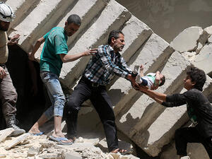 Syrians evacuate a toddler from a destroyed building following a reported air strike on the rebel-held neighbourhood of al-Kalasa in the northern Syrian city of Aleppo, on April 28, 2016. (AFP/File)
