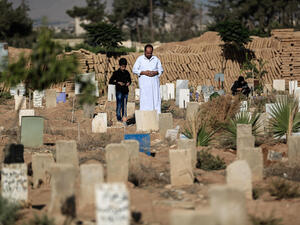 A Syrian man and his son pray over the grave of a relative at a cemetery. (AFP/File)