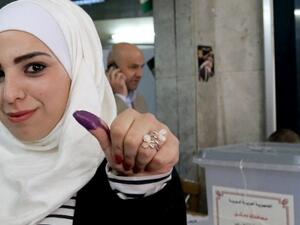 A Syrian woman shows her ink stained thumb after voting at a polling station during parliamentary. (AFP/File)
