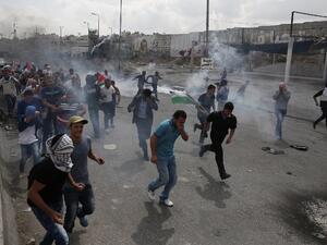 Palestinians run from tear gas smoke during clashes with Israeli security forces at the Qalandiya checkpoint. (AFP/File)