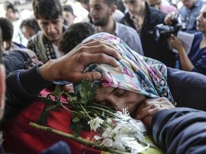 A woman places her head on the coffin of a victim at a funeral in Istanbul Monday, October 12, 2015. (AFP/Yasin Akgul)