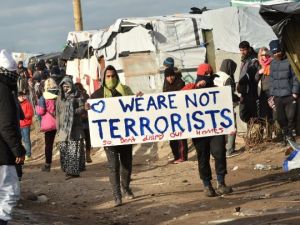 Refugees hold a sign reading “we are not terrorists” during the dismantling of the “jungle” refugee camp in Calais, France, in February 2016. (AFP/Philippe Huguen)