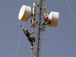 مقاتل من المناوئين للقذافي يشير بعلامة النصر بعد ان رفع علم المجلس الوطني الانتقالي على برج للاتصالات في بلدة تبعد 15 كيلومترا شمالي بني وليد 