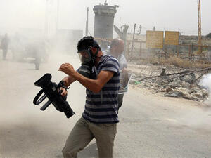 Palestinian journalists run for cover from tear gas canisters fired by Israeli forces during a demonstration in support of Palestinian journalists on the occasion of the World Press Freedom day. (AFP/File) 