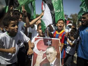 Palestinian supporters of the Hamas movement hold portraits of Turkish President Recep Tayyip Erdogan as they shout slogans against the military coup. (AFP/File) 