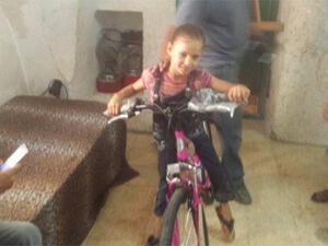 Anwar Burqan is seen smiling with her new bicycle gifted to her by Sami Jolles. (Twitter)