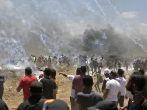 Palestinian protesters run for cover from tear gas during clashes with Israeli forces near the border between the Gaza strip and Israel east of Gaza City on May 14, 2018, as Palestinians protest over the inauguration of the US embassy following its controversial move to Jerusalem. (MAHMUD HAMS/ AFP)