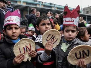 Palestinian children hold bread patties during a protest against aid cuts, outside the United Nations' offices in Khan Yunis in the southern Gaza Strip on January 28, 2018. (Said Khatib/AFP)