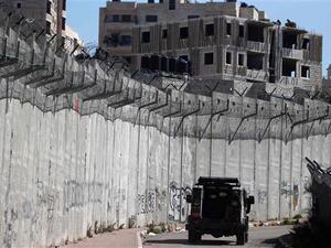 An Israeli police car patrols along a section of Israel’s Apartheid Wall that separates the West Bank city of al-Ram (L) from east al-Quds (Jerusalem) (R) on February 24, 2016. (AFP)