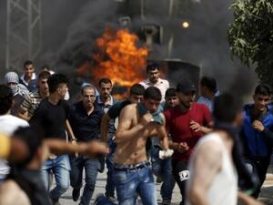 Palestinian youths run from the path of an Israeli army bulldozer during clashes in the village of Koubar, west of Ramallah, on July 22, 2017, as Israeli forces try to close the roads leading to the village. (AFP/ Abbas Momani)